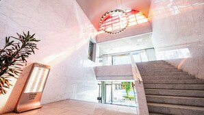 A modern interior with a staircase, a reception desk, and a potted plant. - Resorpia Kumihama (Kyotango)