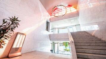 A modern interior with a staircase, a reception desk, and a potted plant.