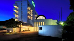 A modern hotel with a prominent sign, a curved entrance, and a well-lit facade. - Resorpia Kumihama (Kyotango)