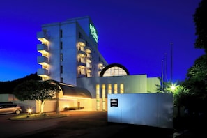 A modern hotel with a prominent sign, a curved entrance, and a well-lit facade. - Resorpia Kumihama (Kyotango)