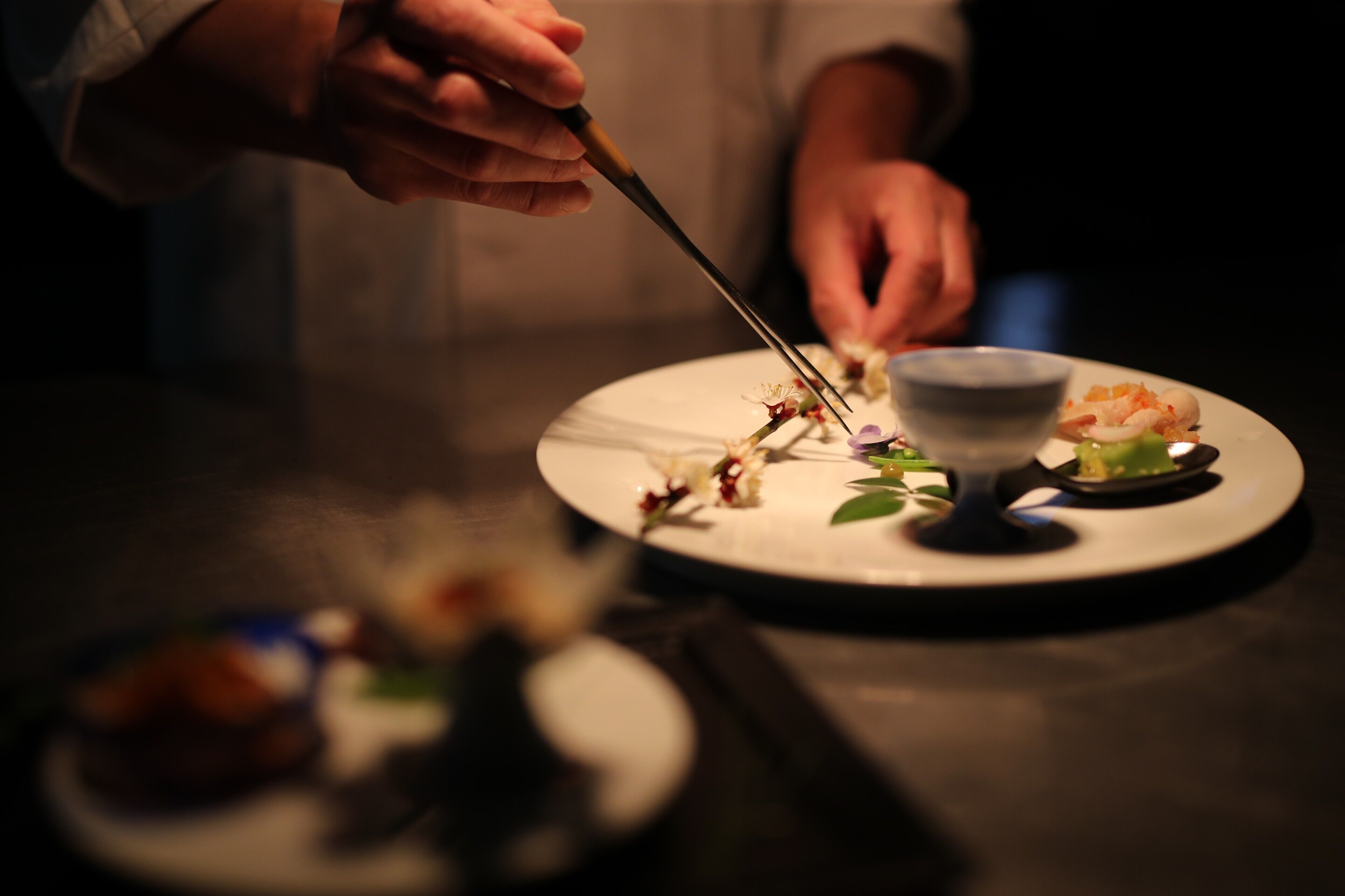 Una persona preparando comida con utensilios sobre un plato.