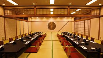 A conference room with long tables, red cushions, and traditional Japanese decor.