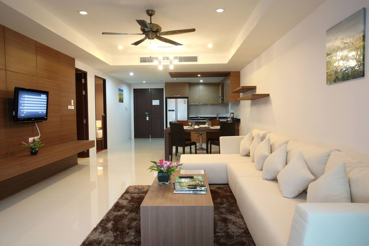 A modern living room with a white sofa, a wooden coffee table, and a ceiling fan.