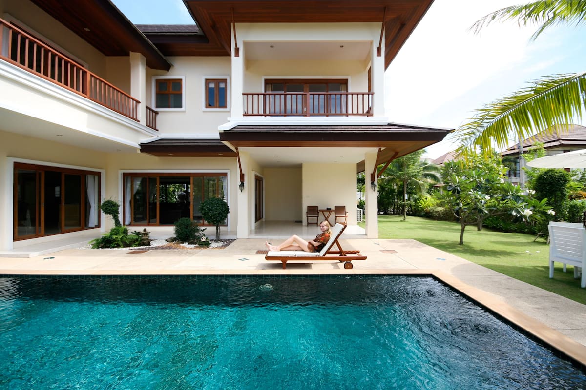 A two-story house with a swimming pool, a balcony, and a well-maintained garden.