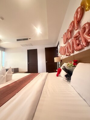 Une chambre d’hôtel avec un lit bien fait, une table de chevet avec une lampe et un mur décoré de ballons.