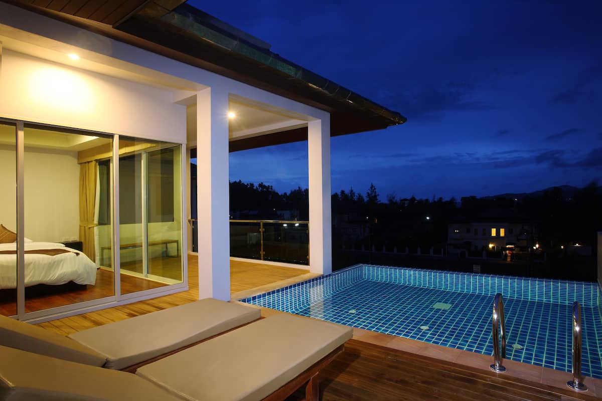 A modern hotel room with a glass sliding door leading to a balcony with a pool.