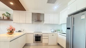 A modern kitchen with white cabinetry, stainless steel appliances, and a tiled floor. - Bangtao Tropical Residence Resort & Spa (Choeng Thale)