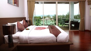 A hotel room with a large bed, a bedside lamp, a view of the outdoors through a sliding glass door, and a balcony with outdoor furniture. - Bangtao Tropical Residence Resort & Spa (Choeng Thale)