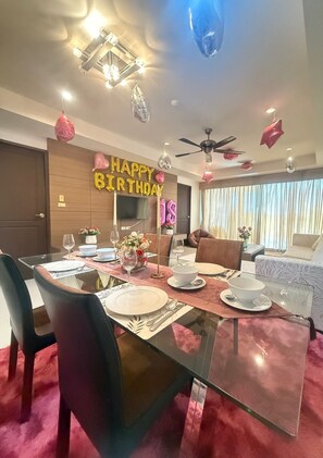 Un coin repas avec une table en verre, des chaises et une pancarte où est écrit « Joyeux anniversaire ».