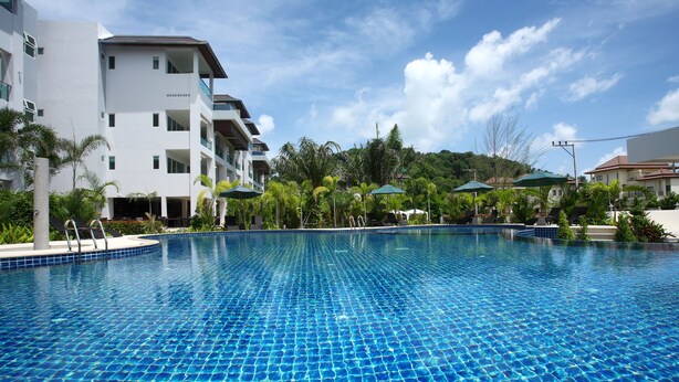A swimming pool with clear blue water, surrounded by white buildings and palm trees. - Bangtao Tropical Residence Resort & Spa (Choeng Thale)
