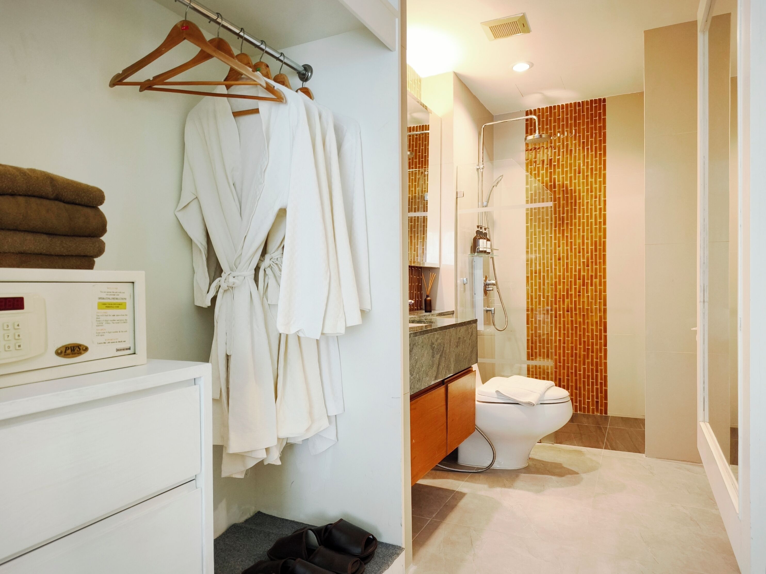 Une salle de bain avec douche, toilettes et un porte-serviettes avec des peignoirs.