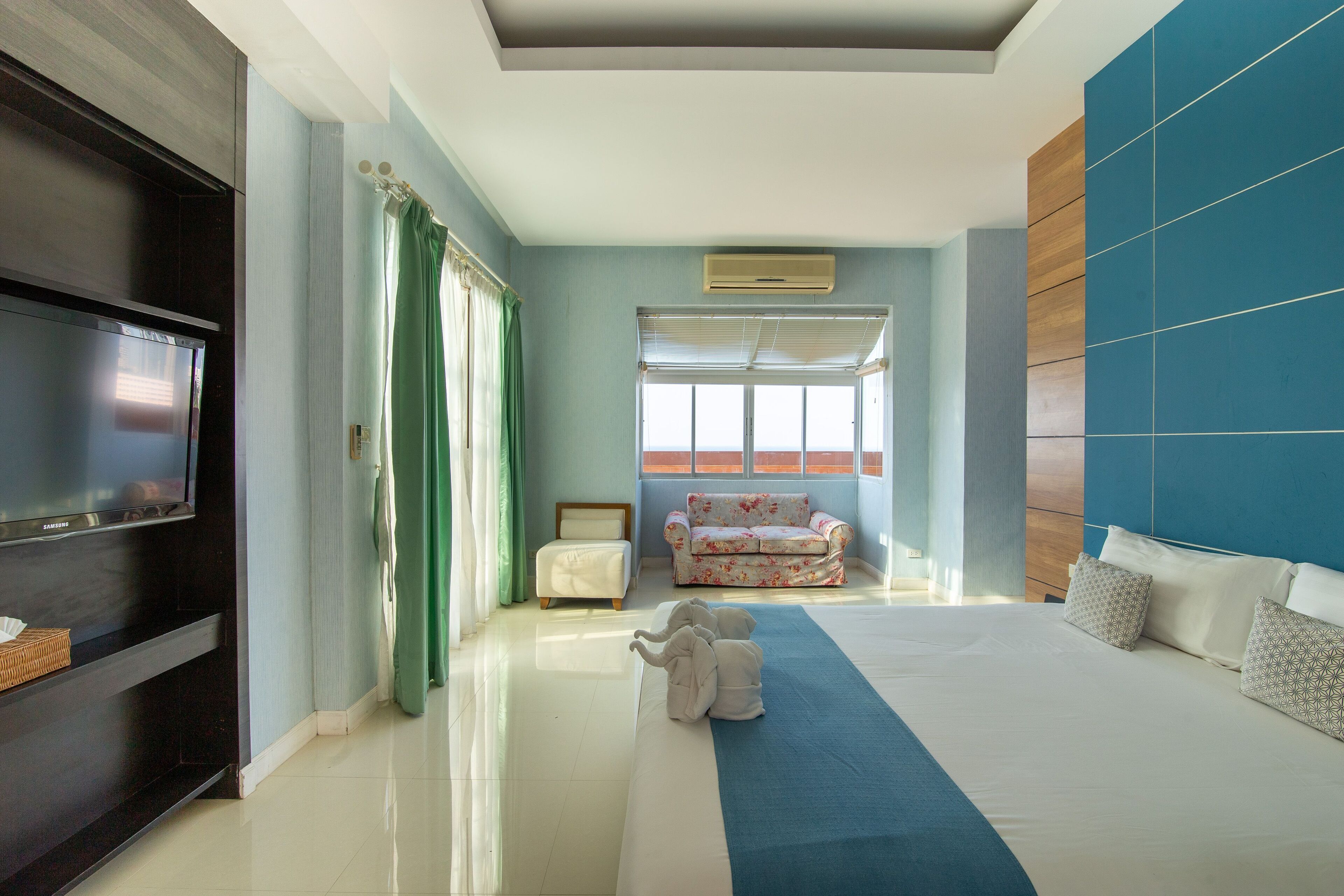 Une chambre d’hôtel avec un grand lit, un téléviseur à écran plat, un canapé et une fenêtre avec des rideaux.