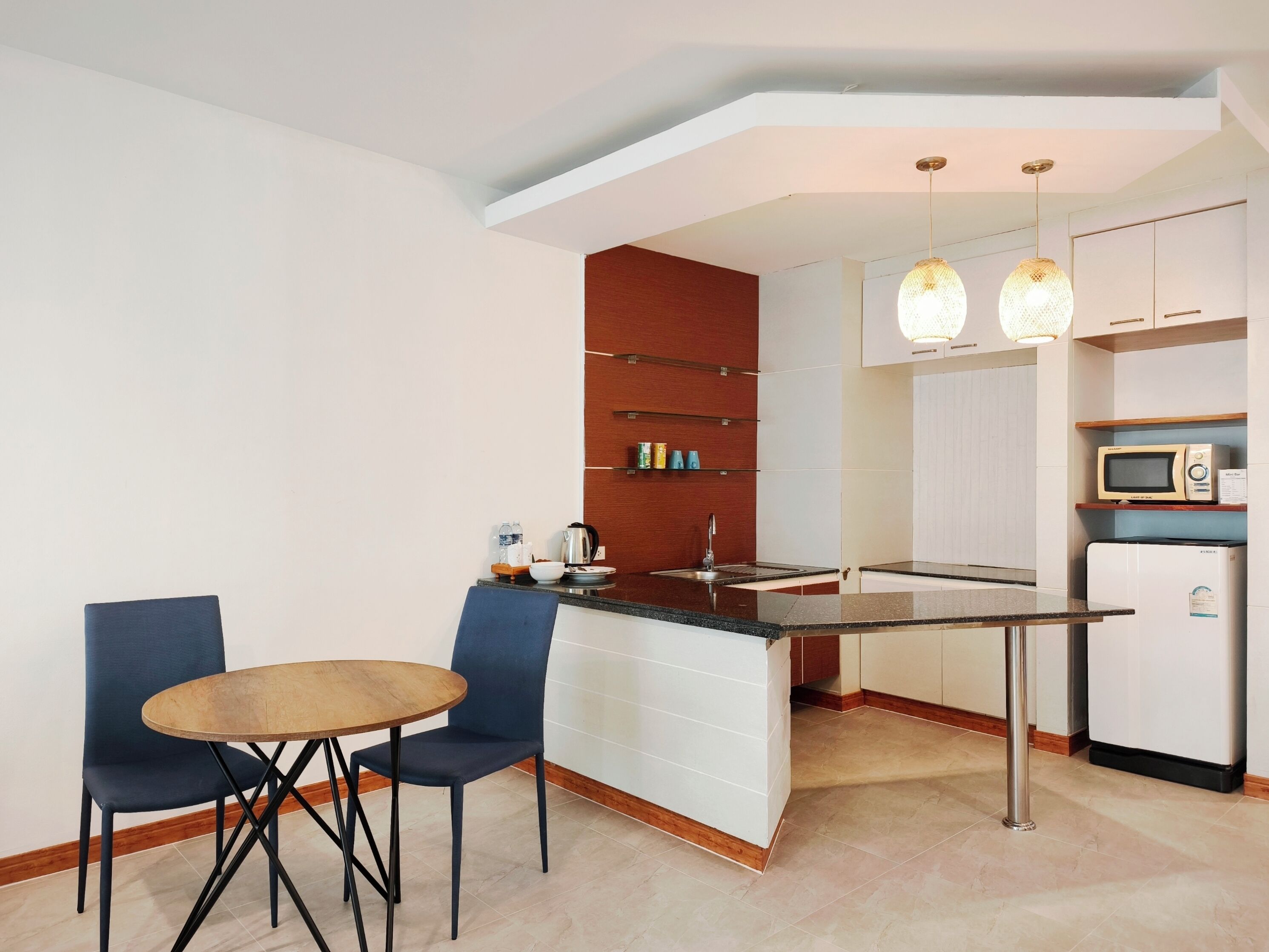 A compact kitchen with a dining area, featuring a small island, modern appliances, and pendant lighting.