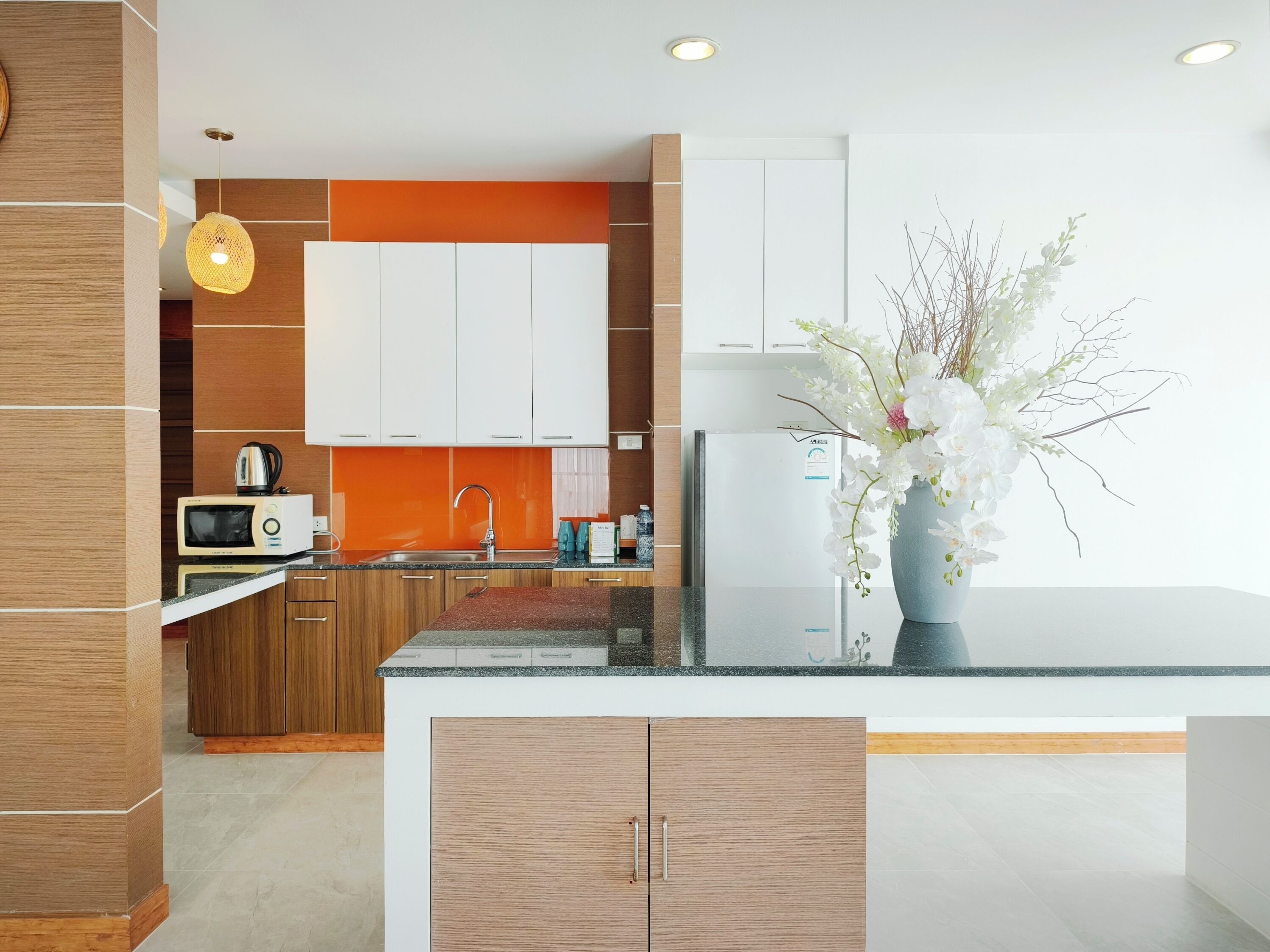 Una cocina moderna con armarios de madera, un refrigerador blanco, un microondas y un lavamanos.