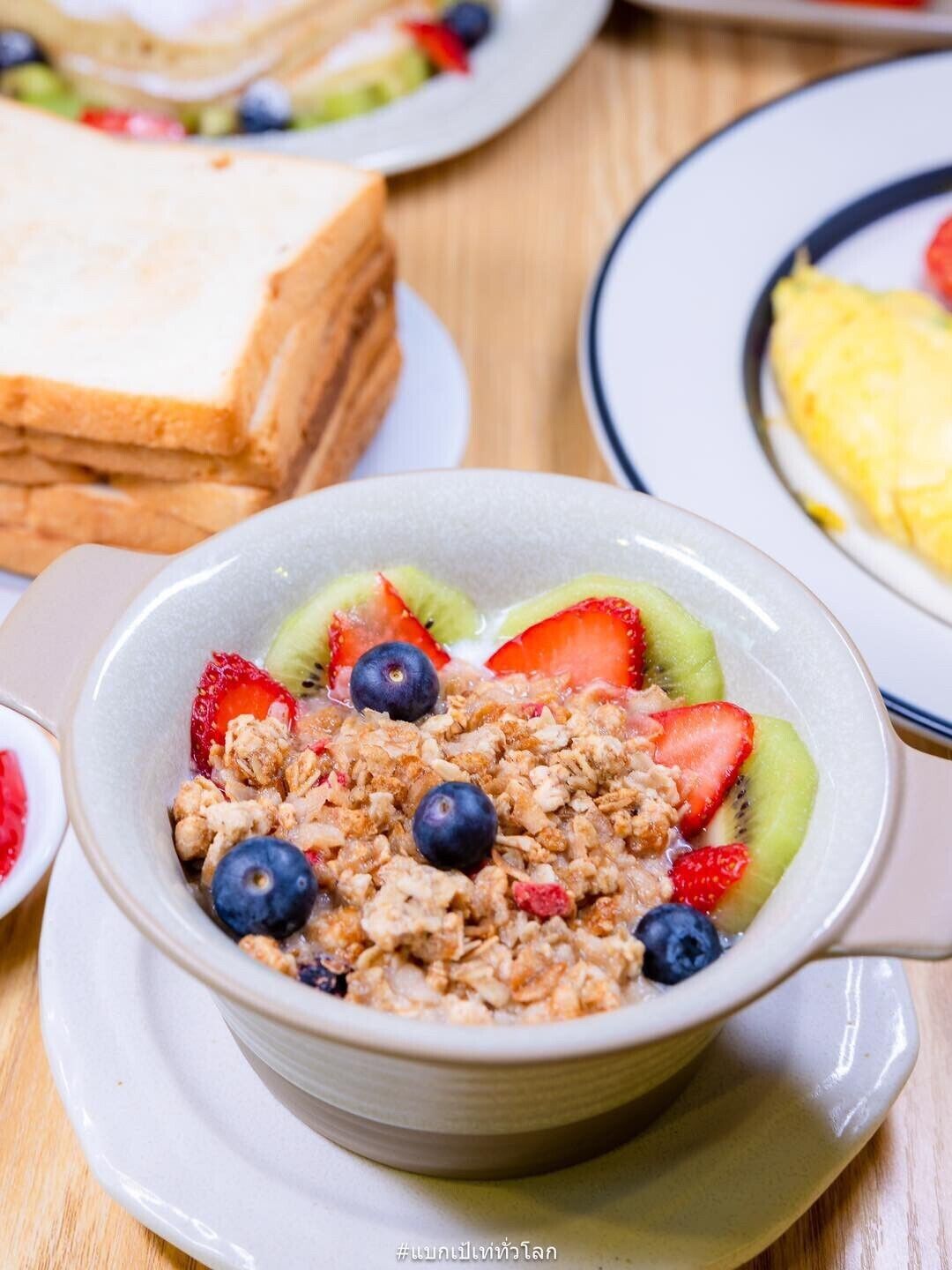 A bowl of cereal with fruits and granola on a plate.
