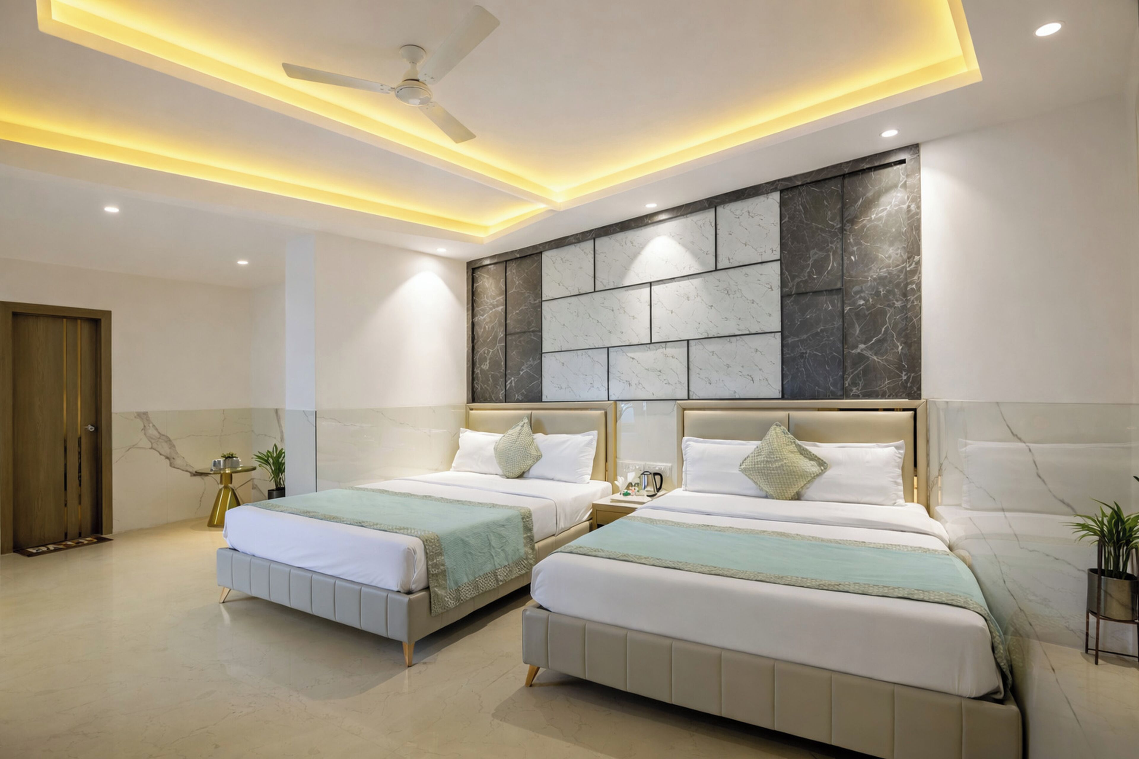 A modern hotel room with two beds, a ceiling fan, recessed lighting, marble wall, and a wooden door.