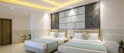 A modern hotel room with two beds, a ceiling fan, recessed lighting, marble wall, and a wooden door.