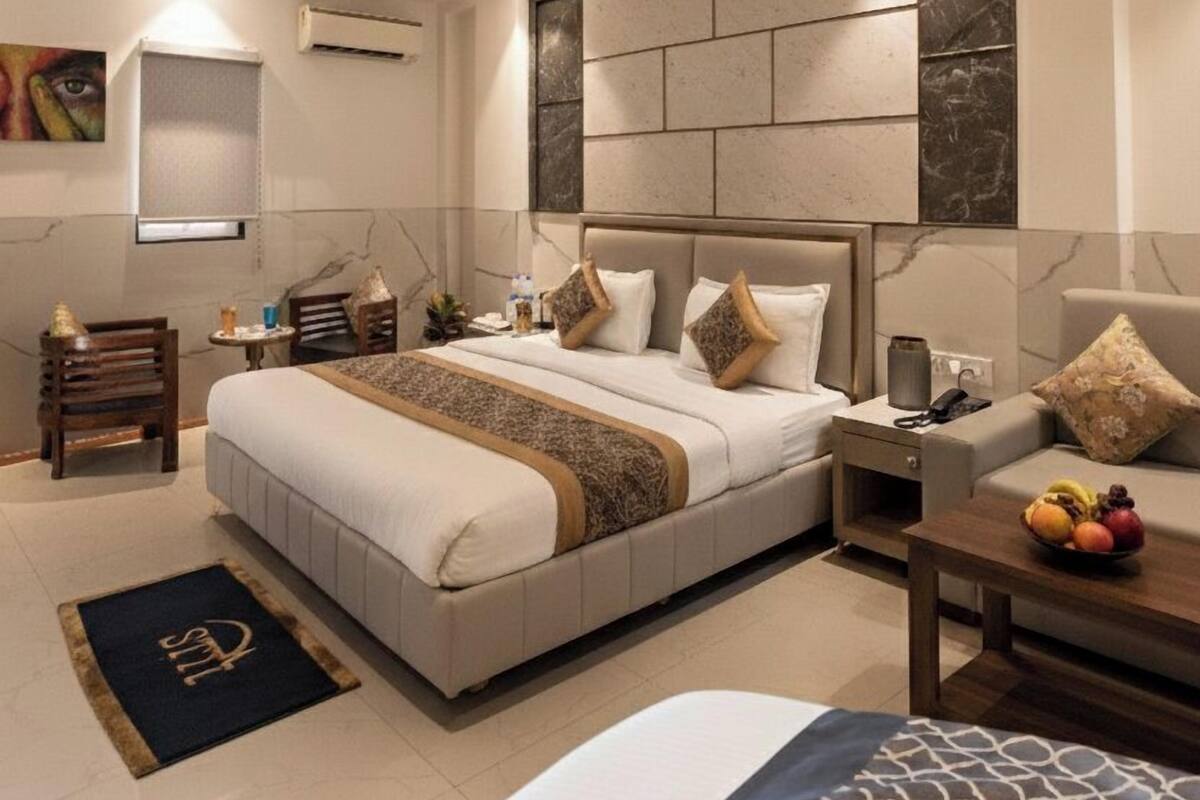 Un dormitorio moderno con una cama grande, ventilador de techo, iluminación empotrada, pared de mármol y una mesita de noche con fruta.