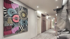 Een moderne hal met wanddecoratie met een patroon, een vloerbedekking en een zithoek met grijze stoelen.