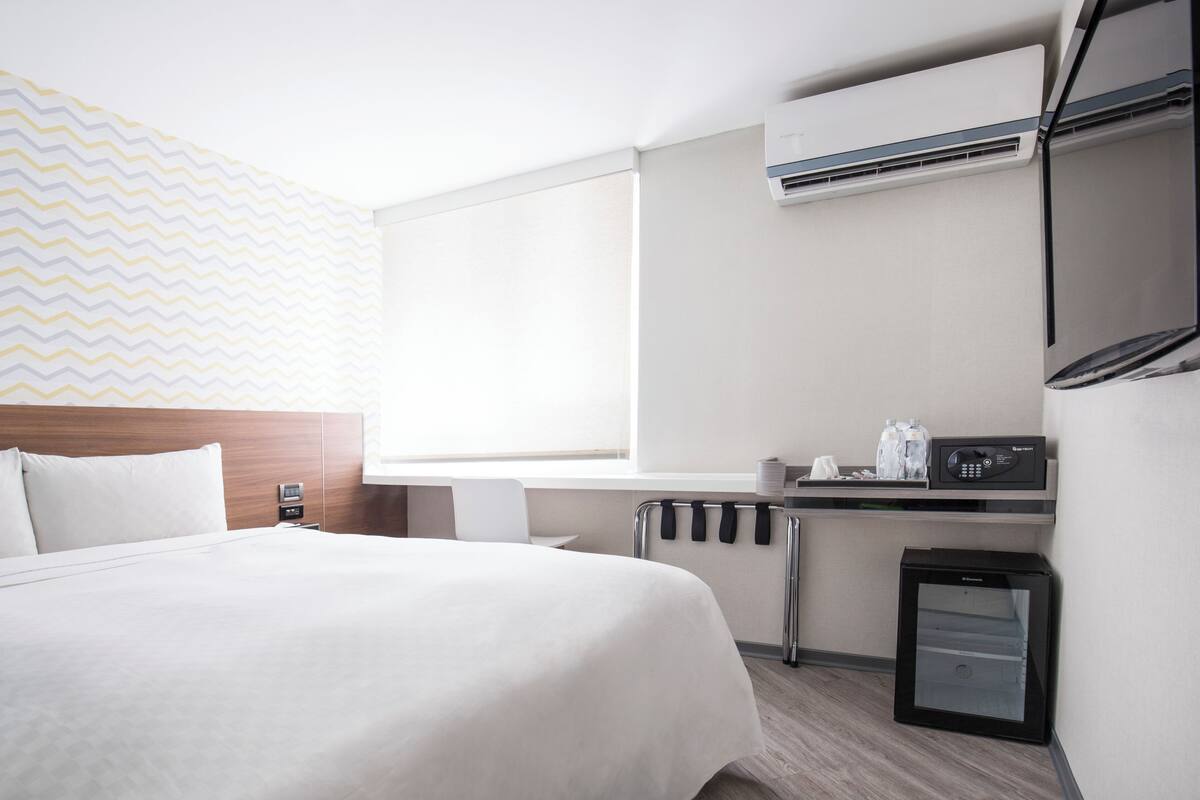 Ein Hotelzimmer mit Bett, Schreibtisch, Mikrowelle und kleinem Kühlschrank.