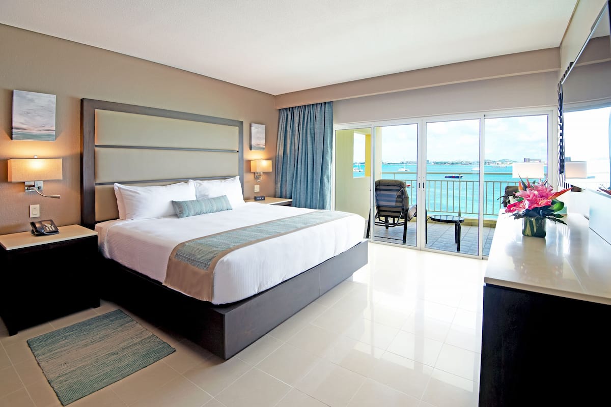 A hotel room with a large bed, a desk, and a view of the sea.