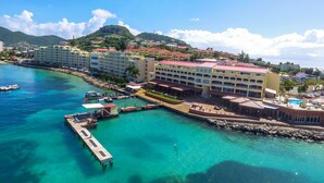 Un hôtel situé sur la côte, composé de plusieurs bâtiments, doté d’un quai et bordé d’eaux turquoise et cristallines.