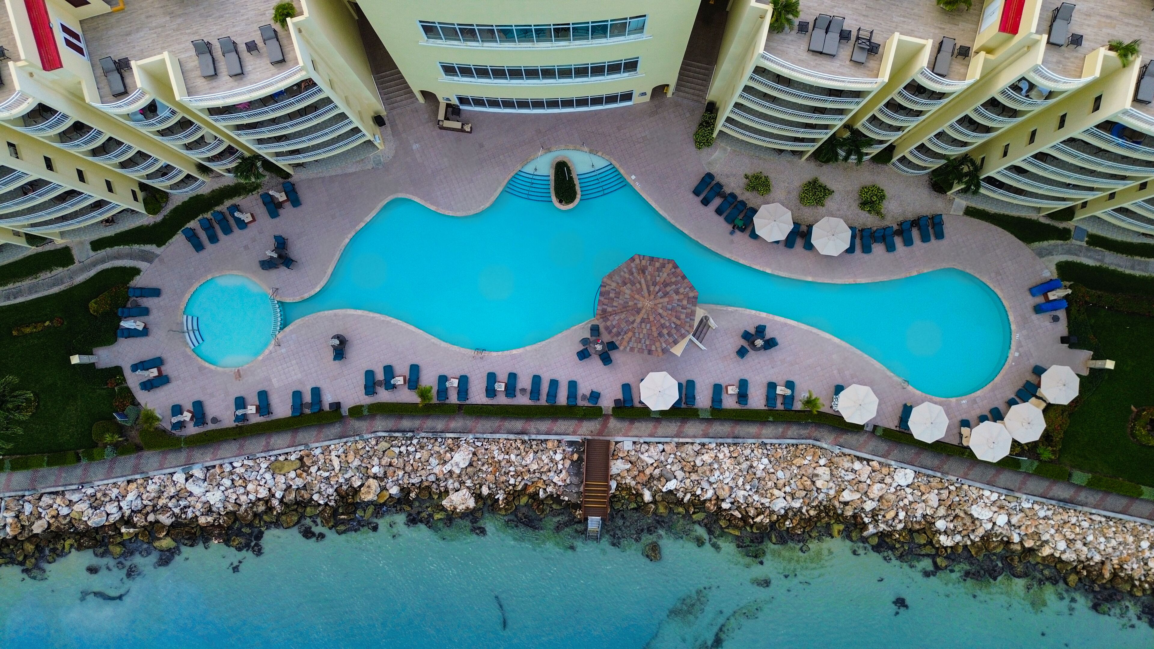 A resort with multiple swimming pools, sun loungers, and a central bridge.