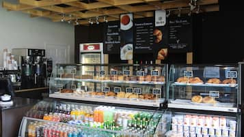 A coffee shop with a variety of beverages and pastries displayed in glass cases.