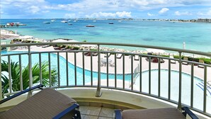 Un balcón con dos sillas que da a una piscina y un puerto deportivo con barcos.