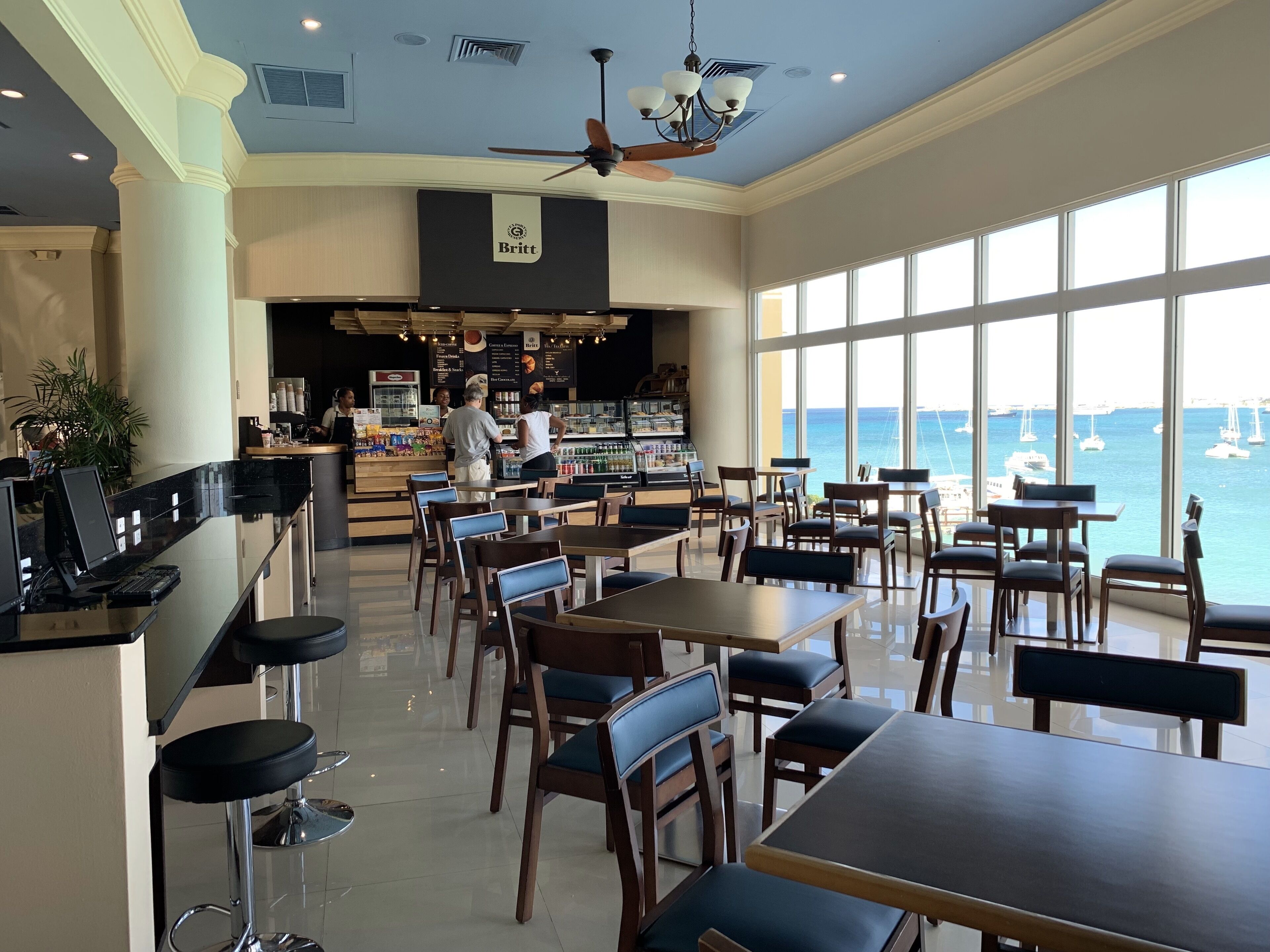 A restaurant with a bar area, seating, and a view of the sea.