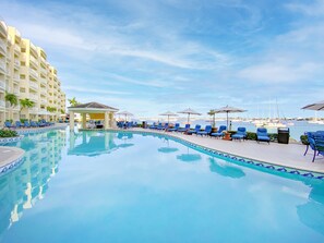 Relax by the pool surrounded by lounge chairs and umbrellas, with a marina view and access to water activities.
