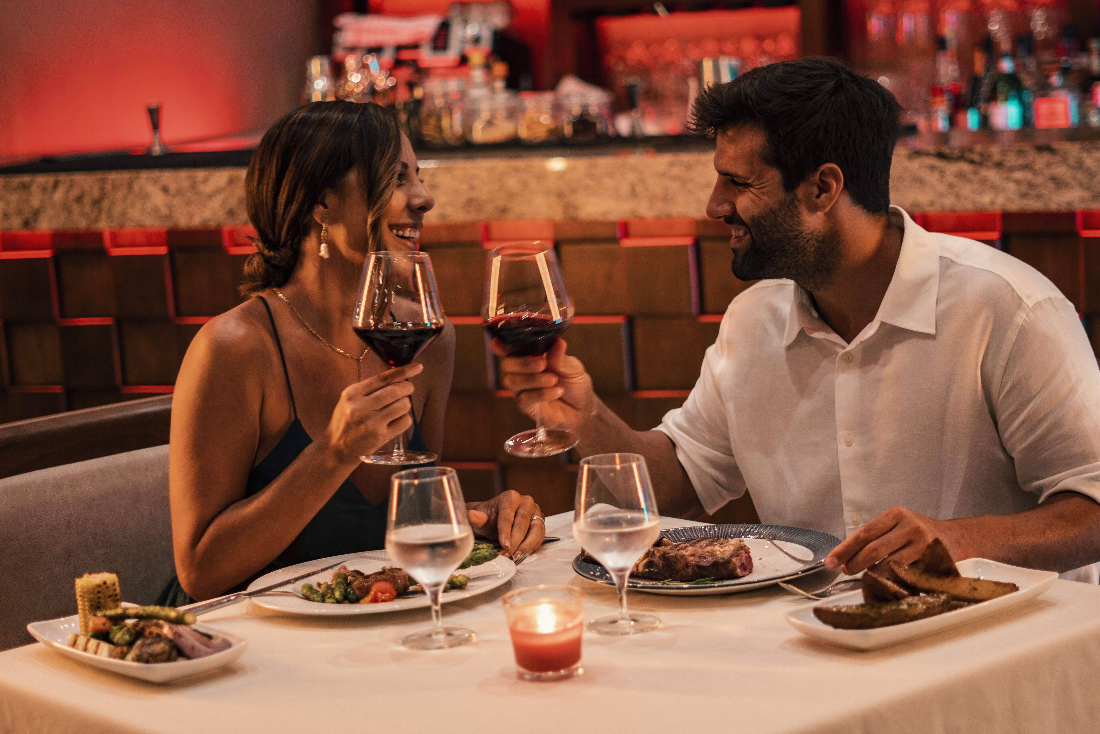 Un couple est assis à une table dans un restaurant, avec un bar visible à l'arrière-plan.