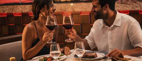 Un couple est assis à une table dans un restaurant, avec un bar visible à l'arrière-plan.