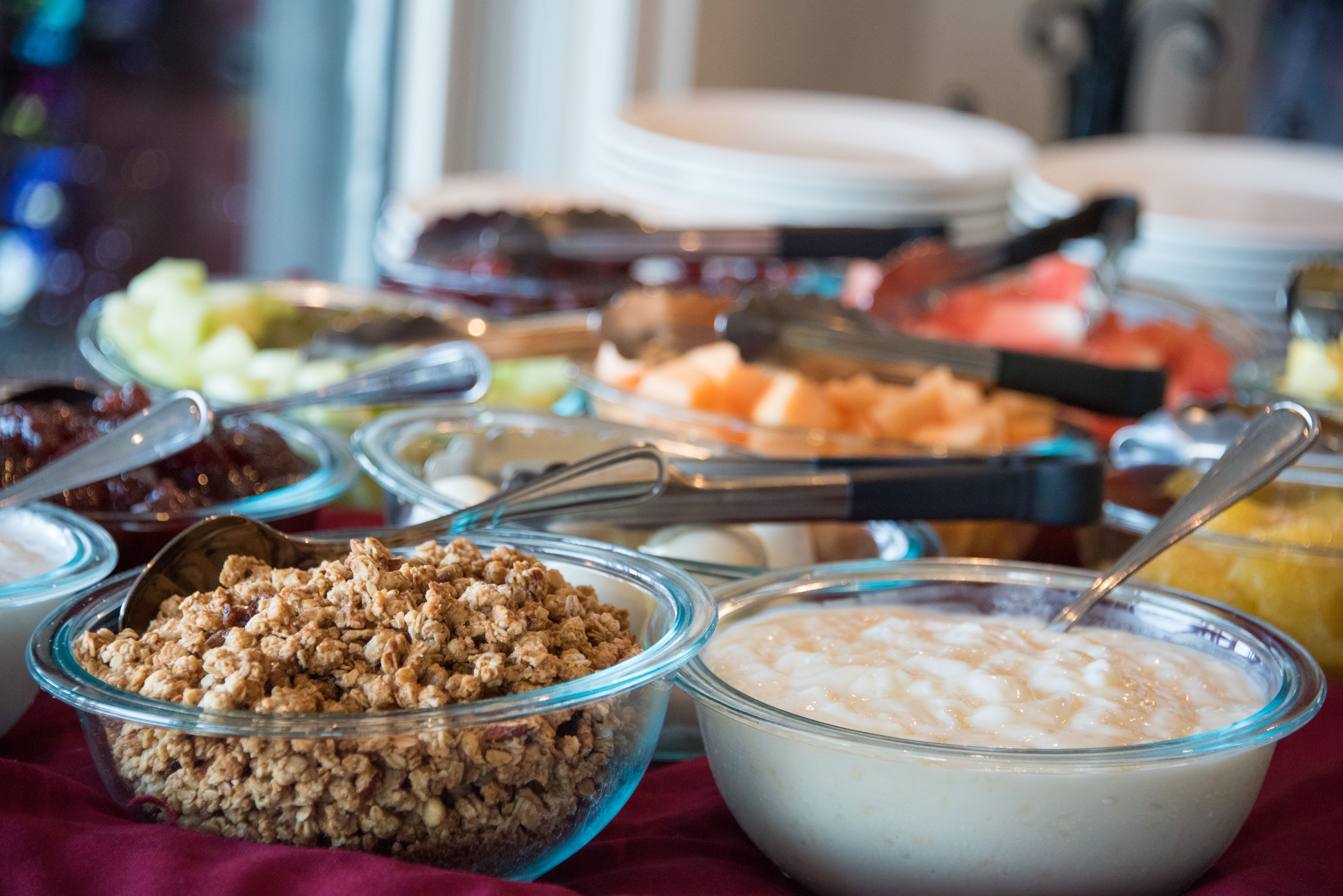 A buffet with various food items including granola, yogurt, and fruits.