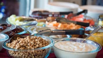 Un bufé con diversos alimentos, incluyendo granola, yogur y frutas.