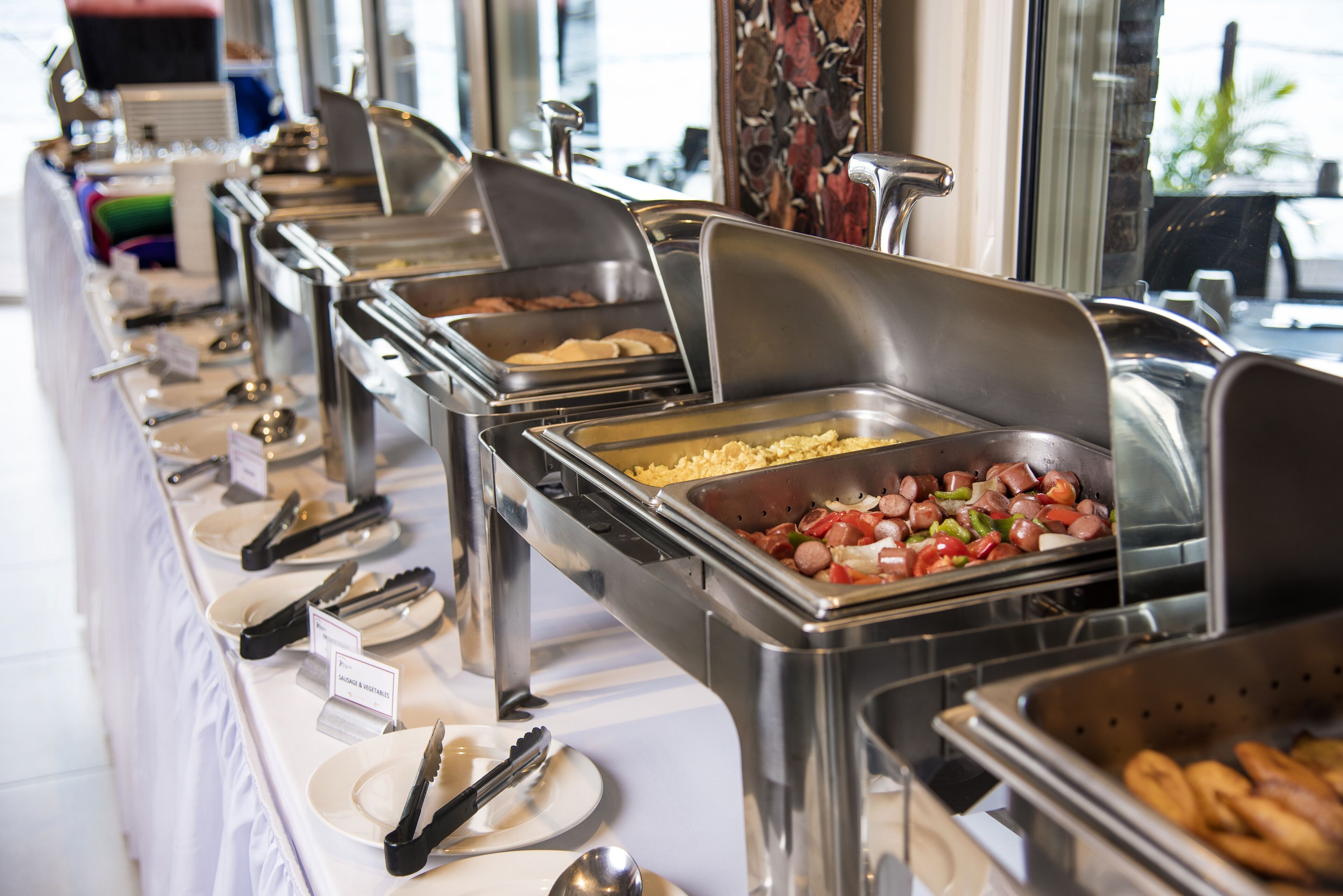 A buffet setup with various food stations, including a salad bar, a hot dog station, and a fruit display.