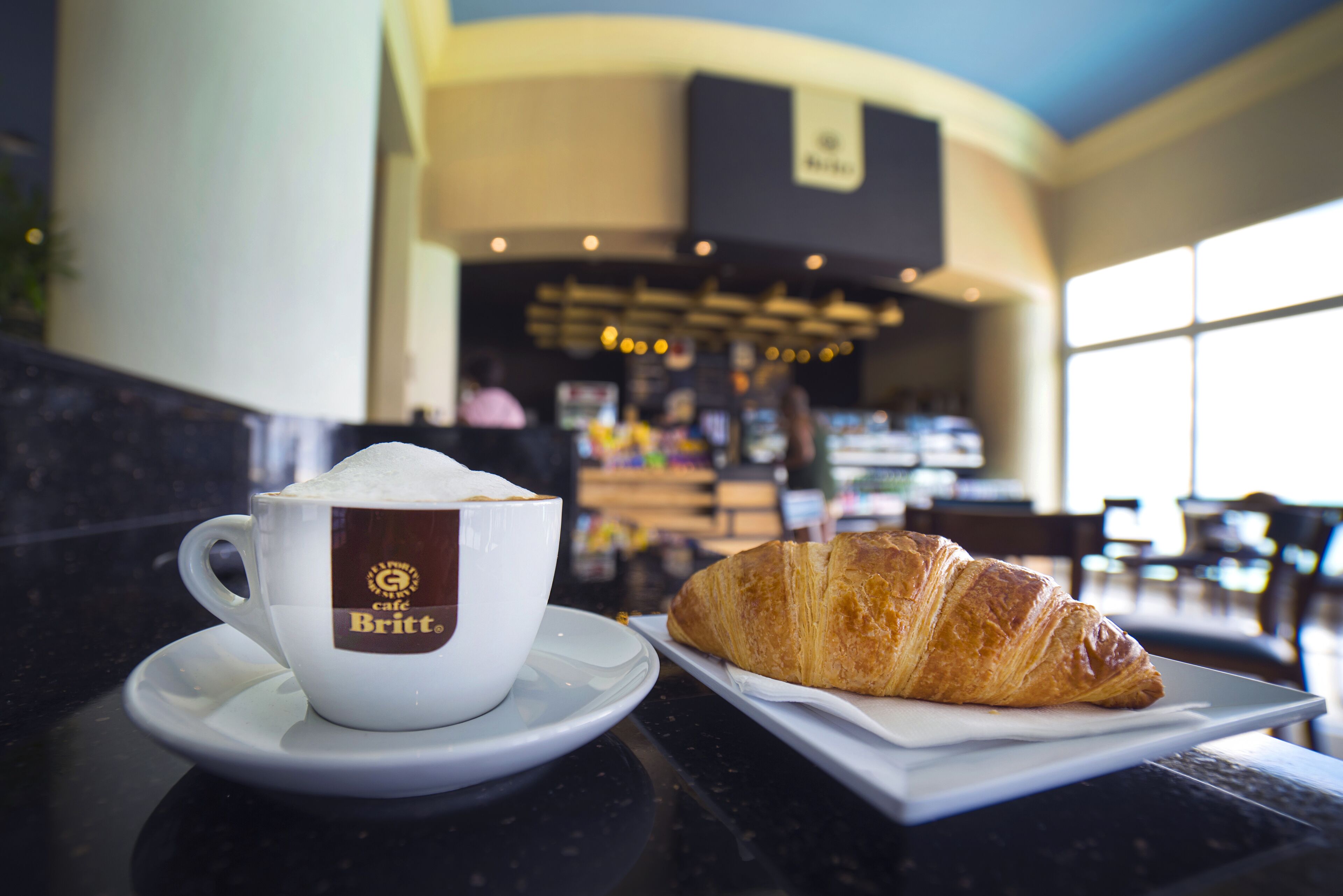 A cup of coffee and a croissant on a table in a cafe.