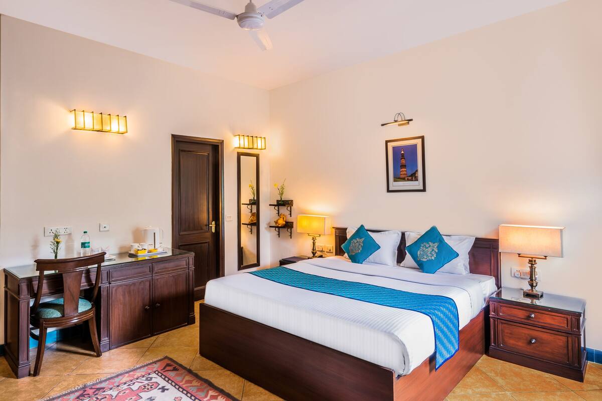 A hotel room with a large bed, bedside tables, a desk, and a chair.