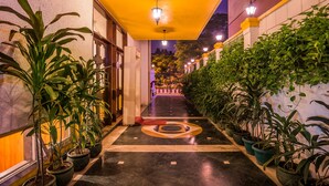 A corridor with potted plants on either side, a patterned floor, and a yellow ceiling. - Home@F37 (New Delhi)
