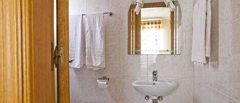 A bathroom with a toilet, sink, and two towels hanging on the wall.