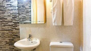 Un baño con pared de piedra, un lavabo, un inodoro y dos toallas colgadas.
