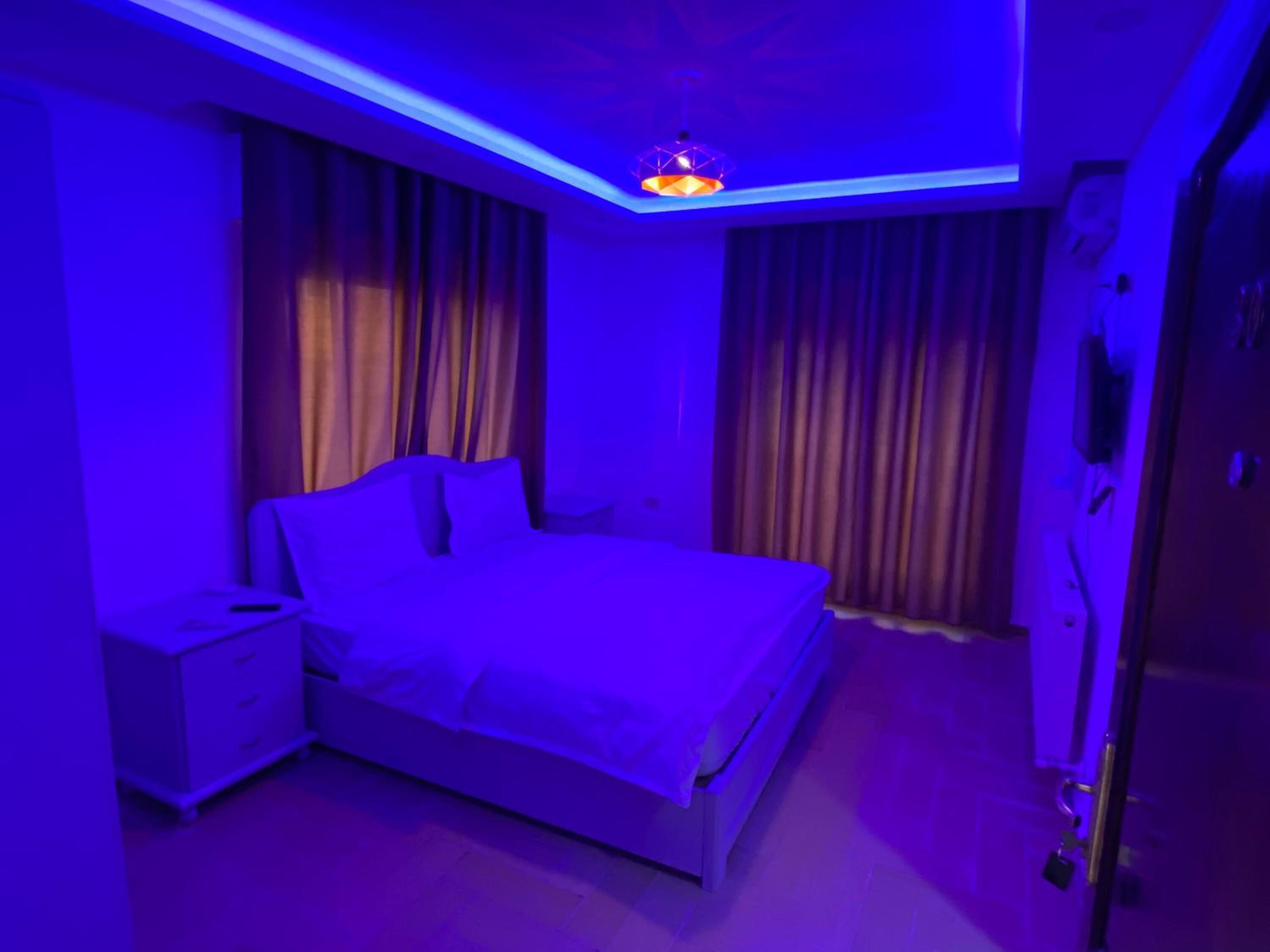 A bedroom with a bed, curtains, a nightstand, and a ceiling light fixture.