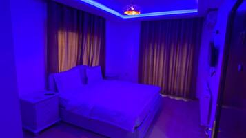 A bedroom with a bed, curtains, a nightstand, and a ceiling light fixture.