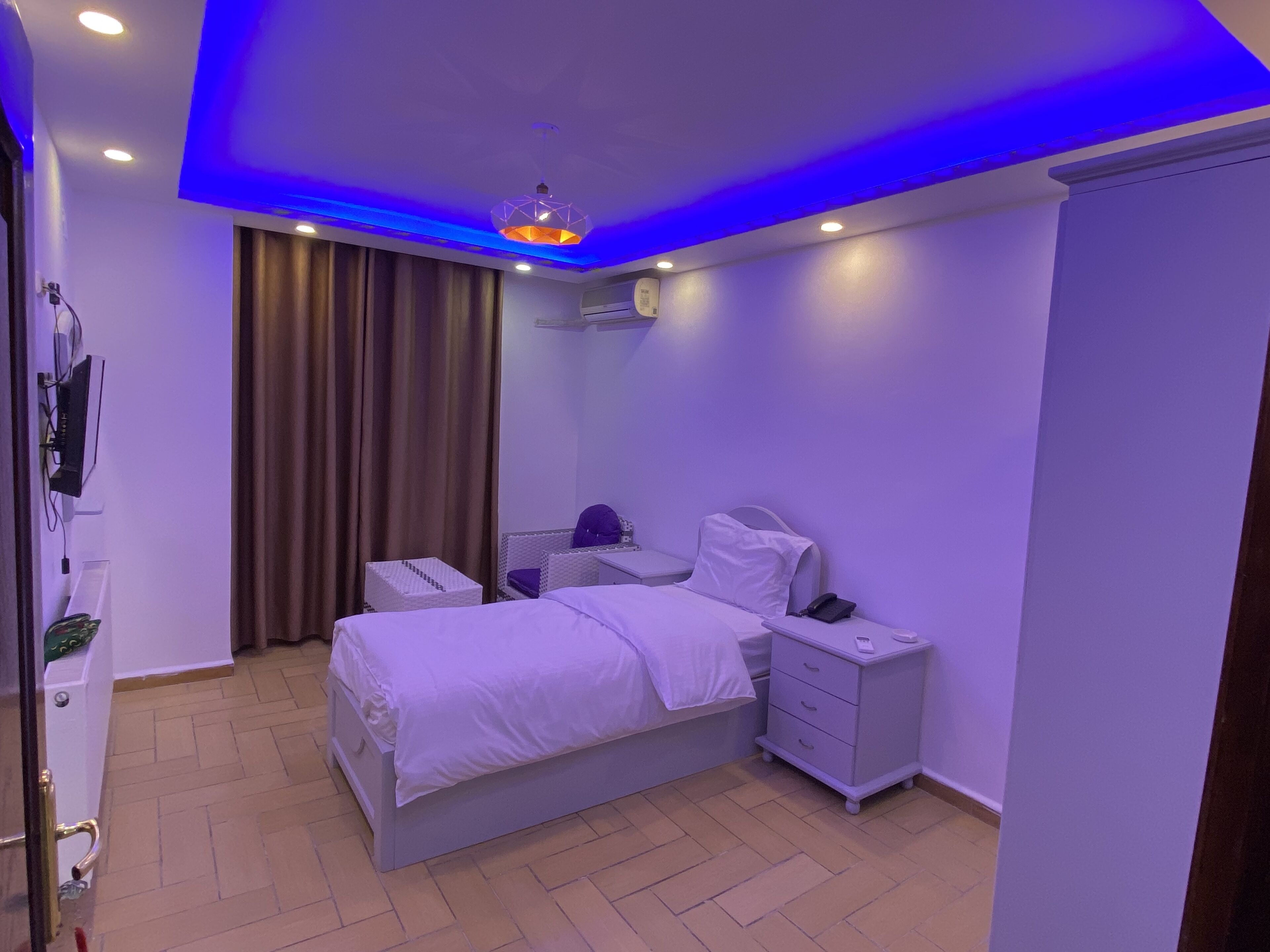 Un dormitorio moderno con cama, mesitas de noche, armario e iluminación en el techo.