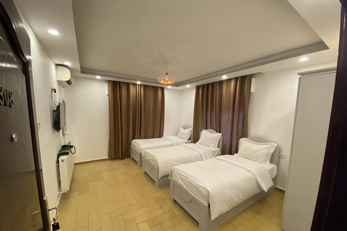 A hotel room with two beds, a ceiling fan, a TV mounted on the wall, and a minibar.