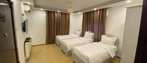 A hotel room with two beds, a ceiling fan, a TV mounted on the wall, and a minibar.