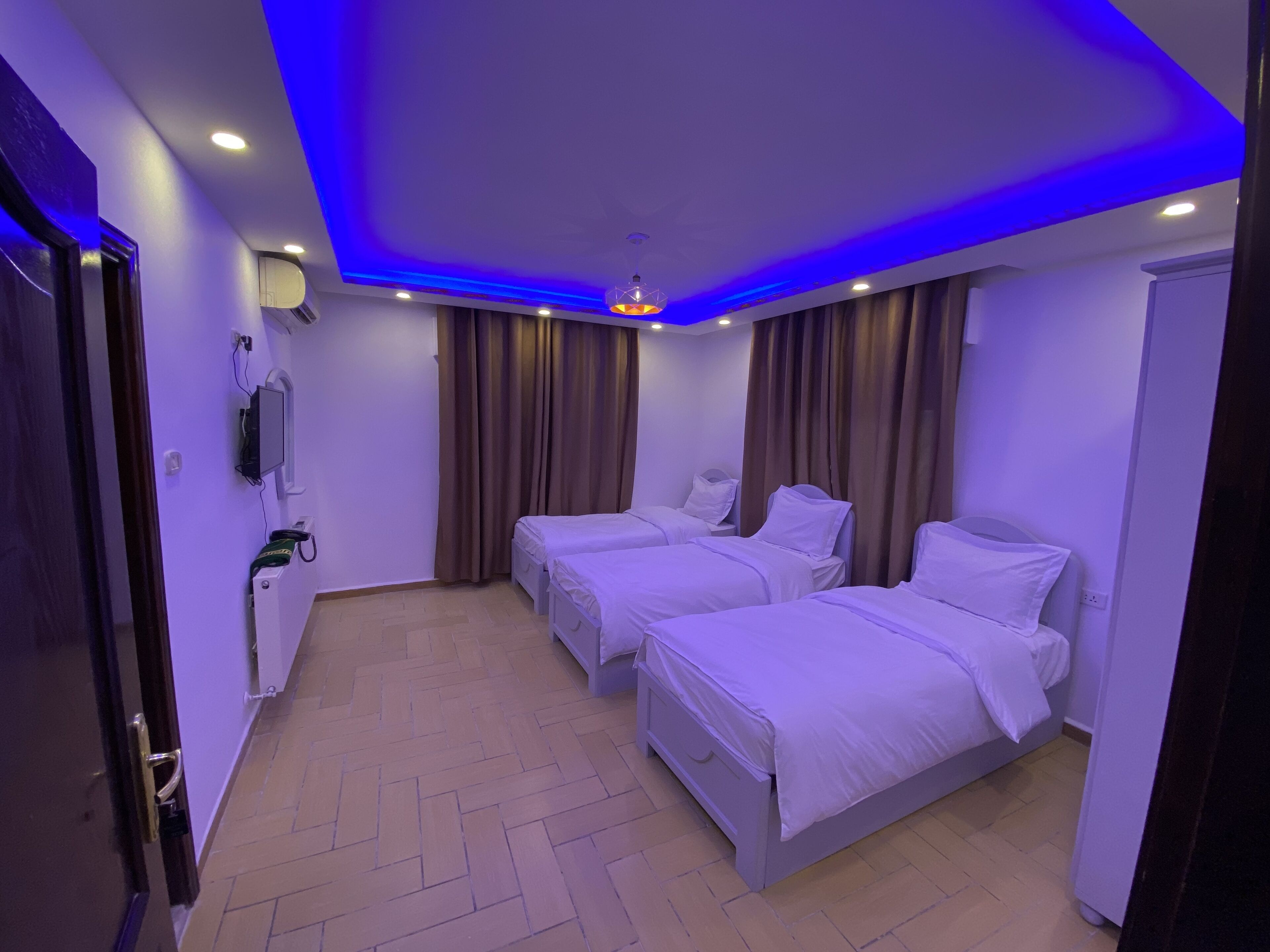 A hotel room with two beds, a flat-screen TV, and a ceiling light fixture.