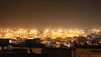 A nighttime cityscape with illuminated buildings and a prominent tower.