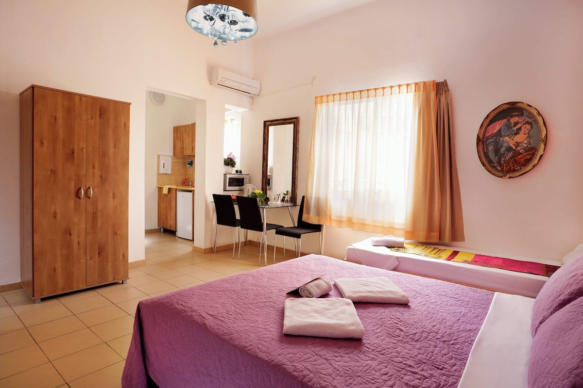 Ein Schlafzimmer mit Bett, Kleiderschrank, Schreibtisch mit Stuhl und einem Fenster mit Vorhängen.