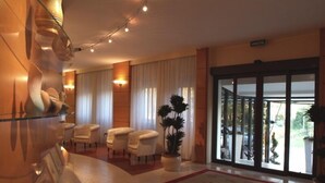 Un'accogliente hall d'albergo con reception, area salotto e ampie finestre.